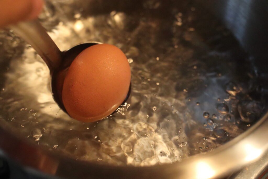 Drop egg in boilign water with a ladle