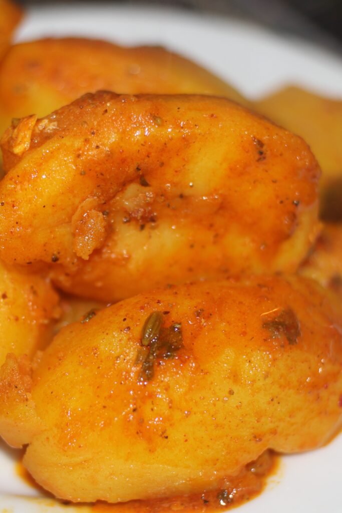 Set aside soft, cooked potatoes from a pot of rich chicken masala gravy.