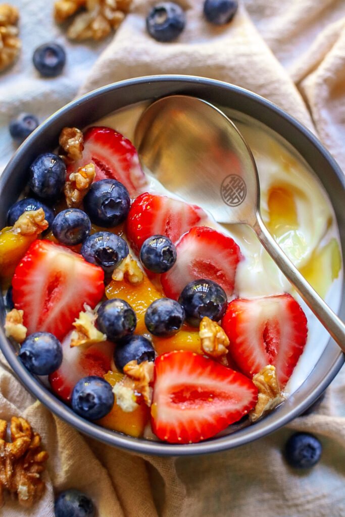 Healthy breakfast bowl with greek yogurt, fruit, honey and walnuts