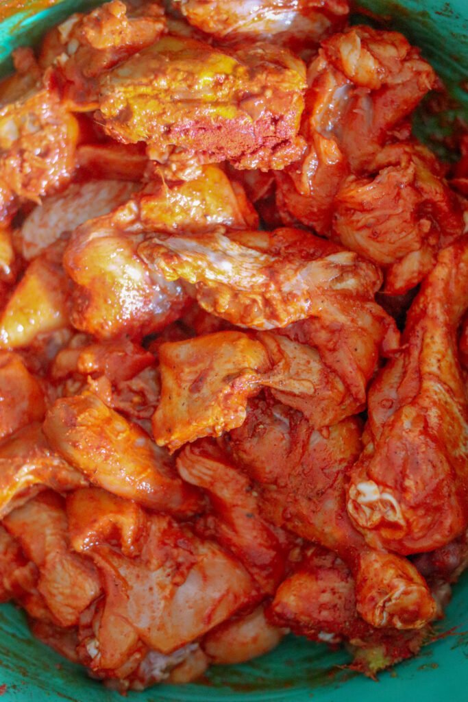 Raw chicken pieces coated in turmeric and Kashmiri chilli powder marinade