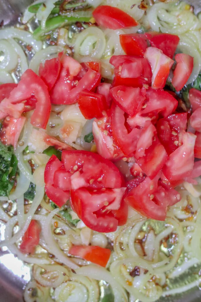 Onions curry leaves garlic and green chillies cooking in oil in a pot