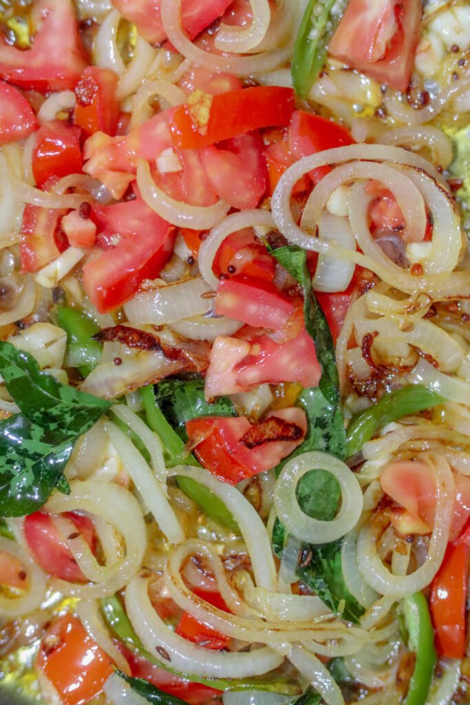 Softened translucent onions with curry leaves and spices as curry base