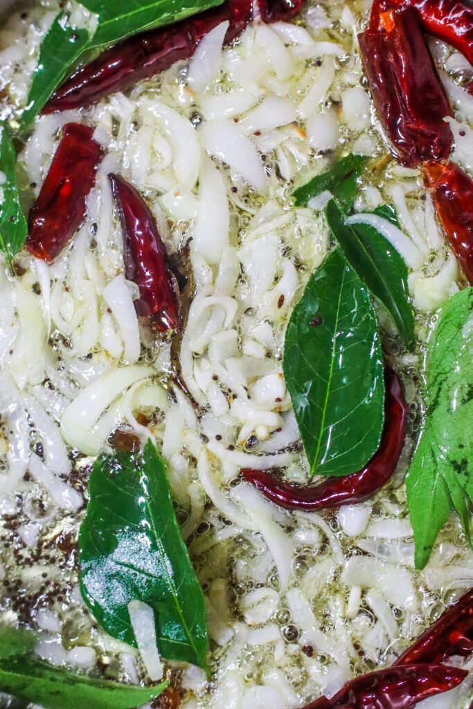 Mustard seeds curry leaves and onions frying in oil for braised butternut