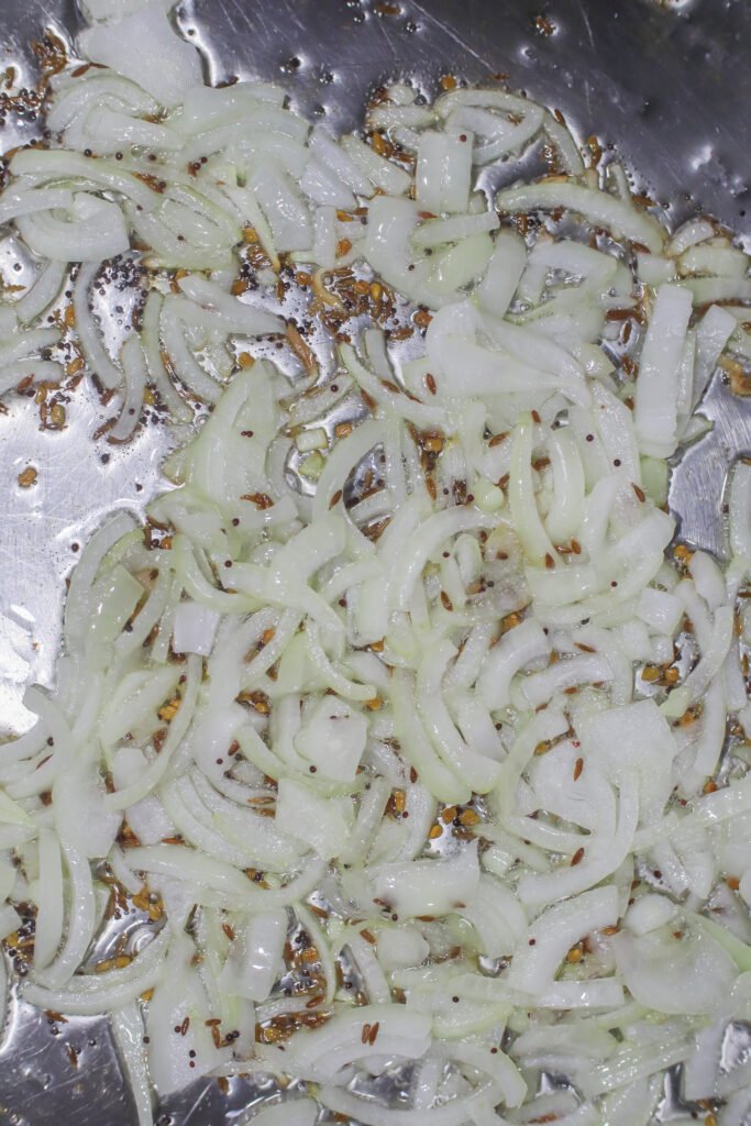caramelised onions with methi, mustard and jeera seeds frying in oil for durban crab curry