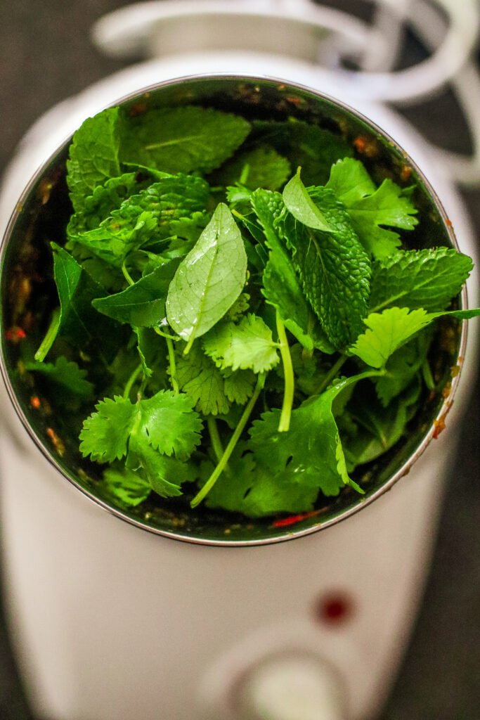 adding fresh mint, curry leaves and coriander to blender