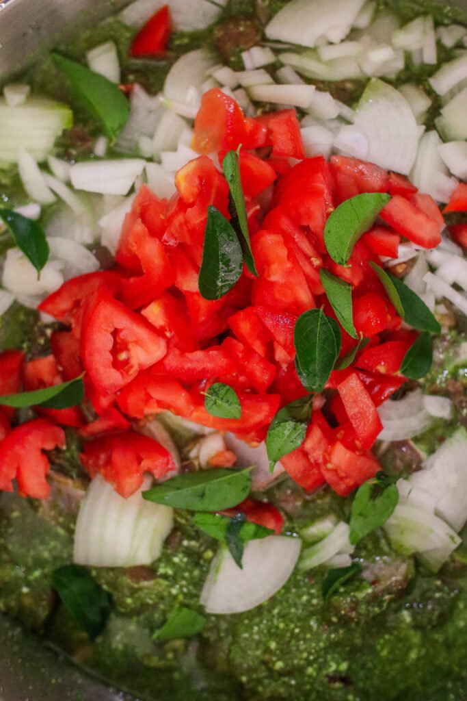 mutton marinating in green marinade, tomatoes, onions curry leaves and maas