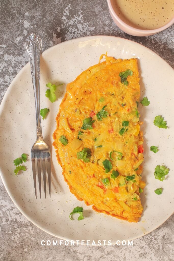 Masala omelette on a plate with a mug of coffee