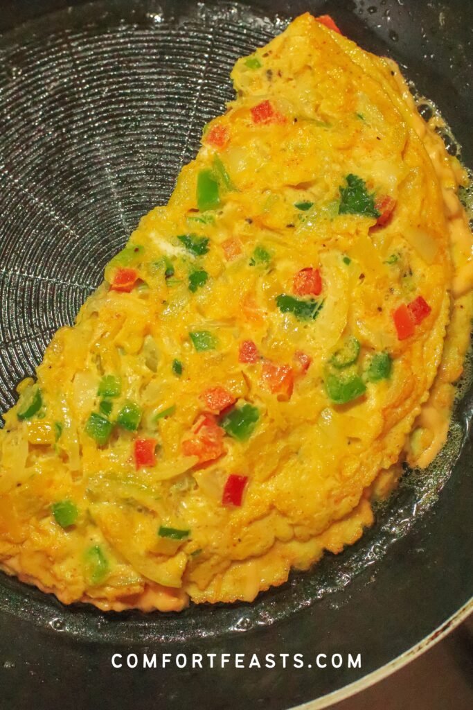 Folded masala omelette with melted cheese in the pan
